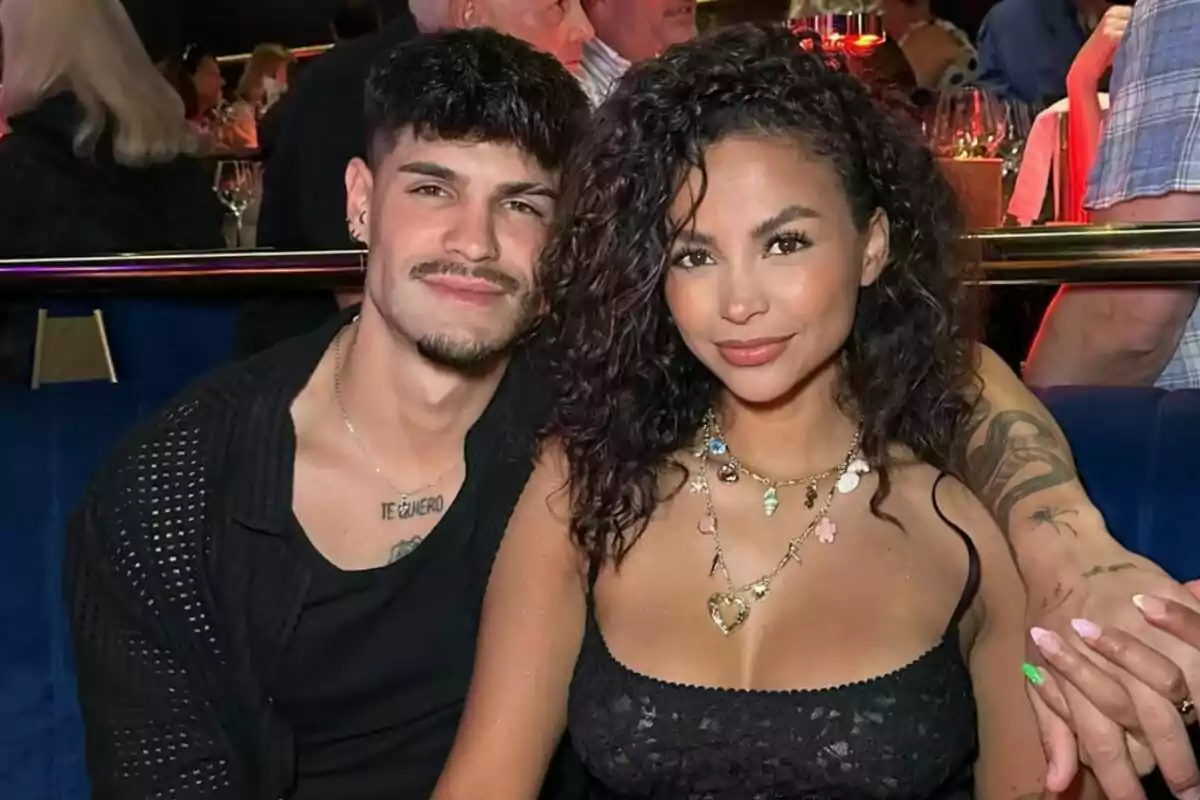 Álvaro i Mayeli asseguts en un restaurant elegant somriuen mentre posen junts per a la foto