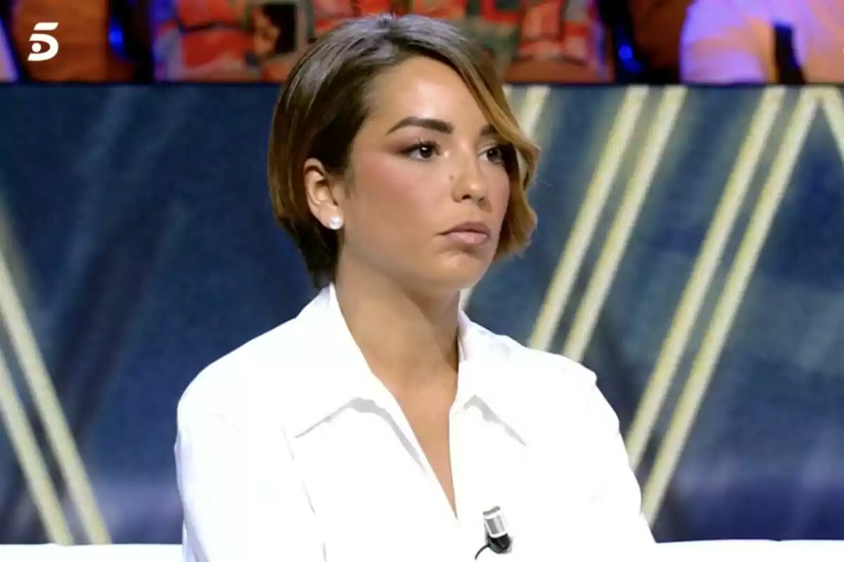 Anita Williams de cabello corto y castaño con camisa blanca sentada en De Viernes con expresión seria Anita Williams de cabello corto y castaño con camisa blanca sentada en De Viernes con expresión seria
