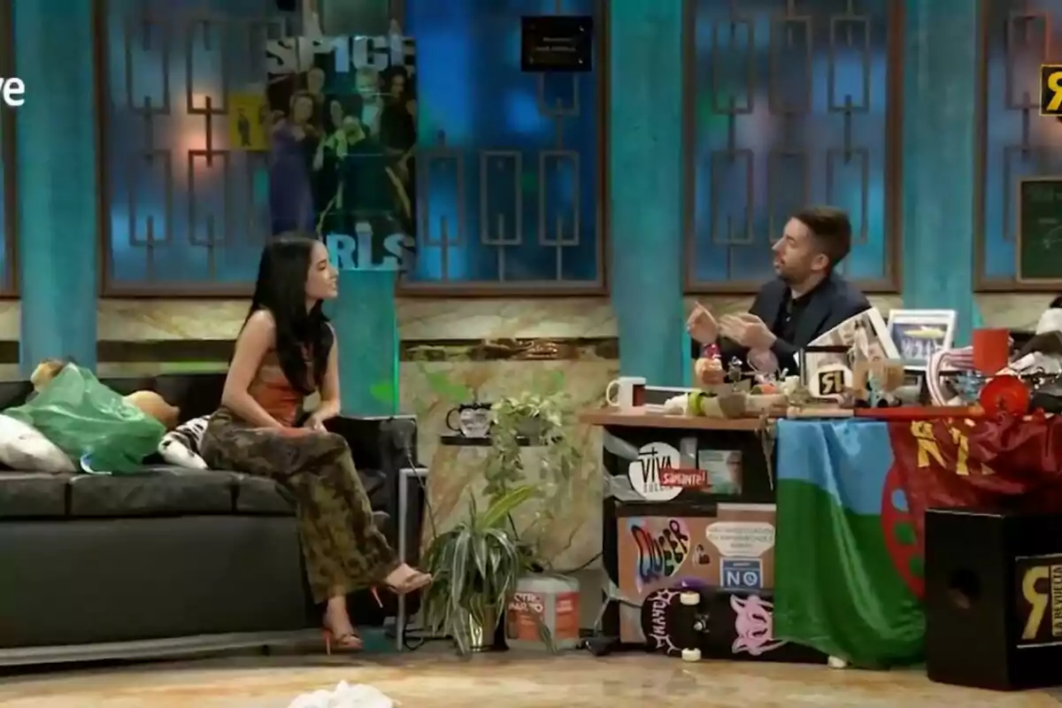 Becky G i David Broncano conversen a 'La Revuelta', decorat amb objectes colorits i un pòster de les Spice Girls al fons.