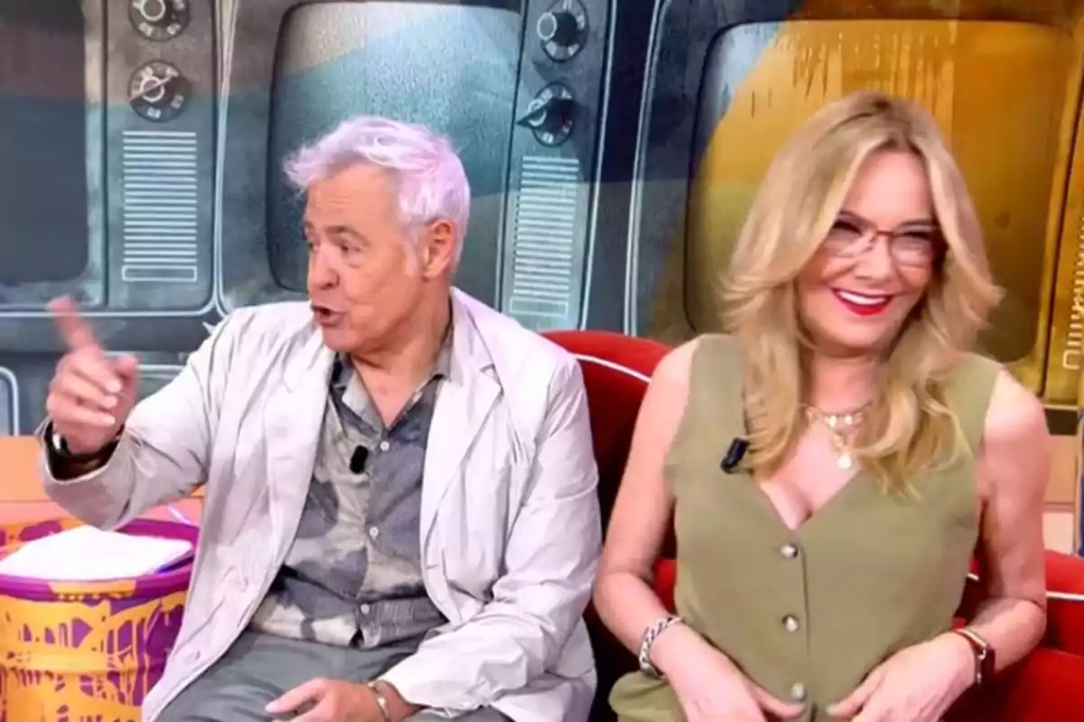 Dues persones assegudes en un plató de televisió, una d’elles gesticulant amb la mà mentre l’altra somriu, amb pantalles antigues de fons.