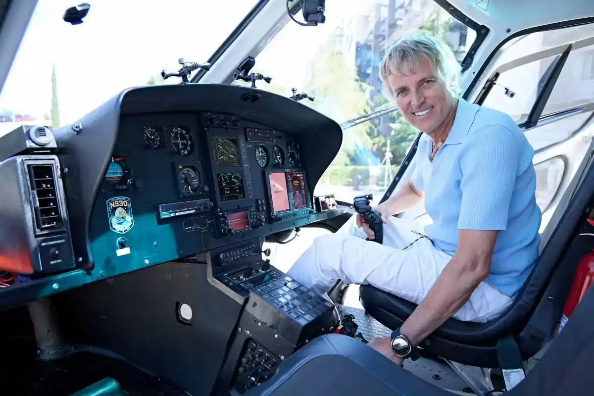 Jesús Calleja sonriente sentado en la cabina de un helicóptero sosteniendo el control de mando ante el estreno de Volando voy, volando vengo