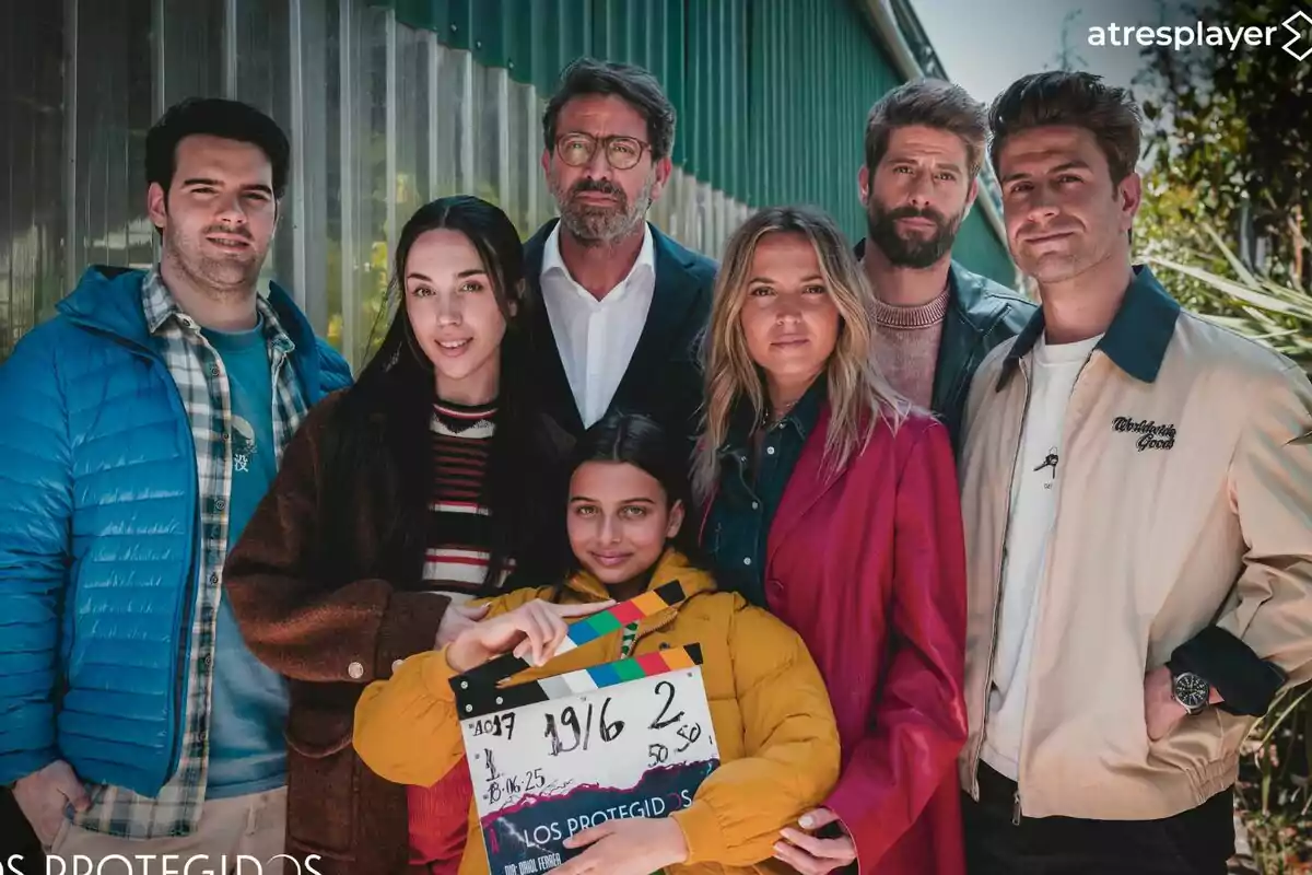 Ana Fernández, Luis Fernández, Mario Marzo, Antonio Garrido, Daniel Avilés, Maggie García i Cosette Silguero posen juntes a l’aire lliure, una d’elles sosté una claqueta de cinema i tots miren a la càmera amb una expressió relaxada de Los Protegidos.