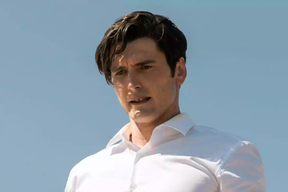 Yon González de cabells foscos amb camisa blanca mirant cap avall amb expressió seriosa i el cel blau de fons a Memento Mori