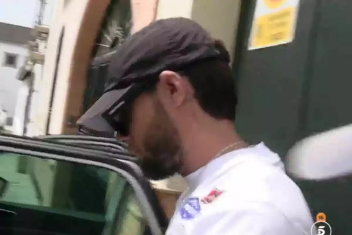 Montoya amb gorra i ulleres de sol entrant a un cotxe en un carrer urbà