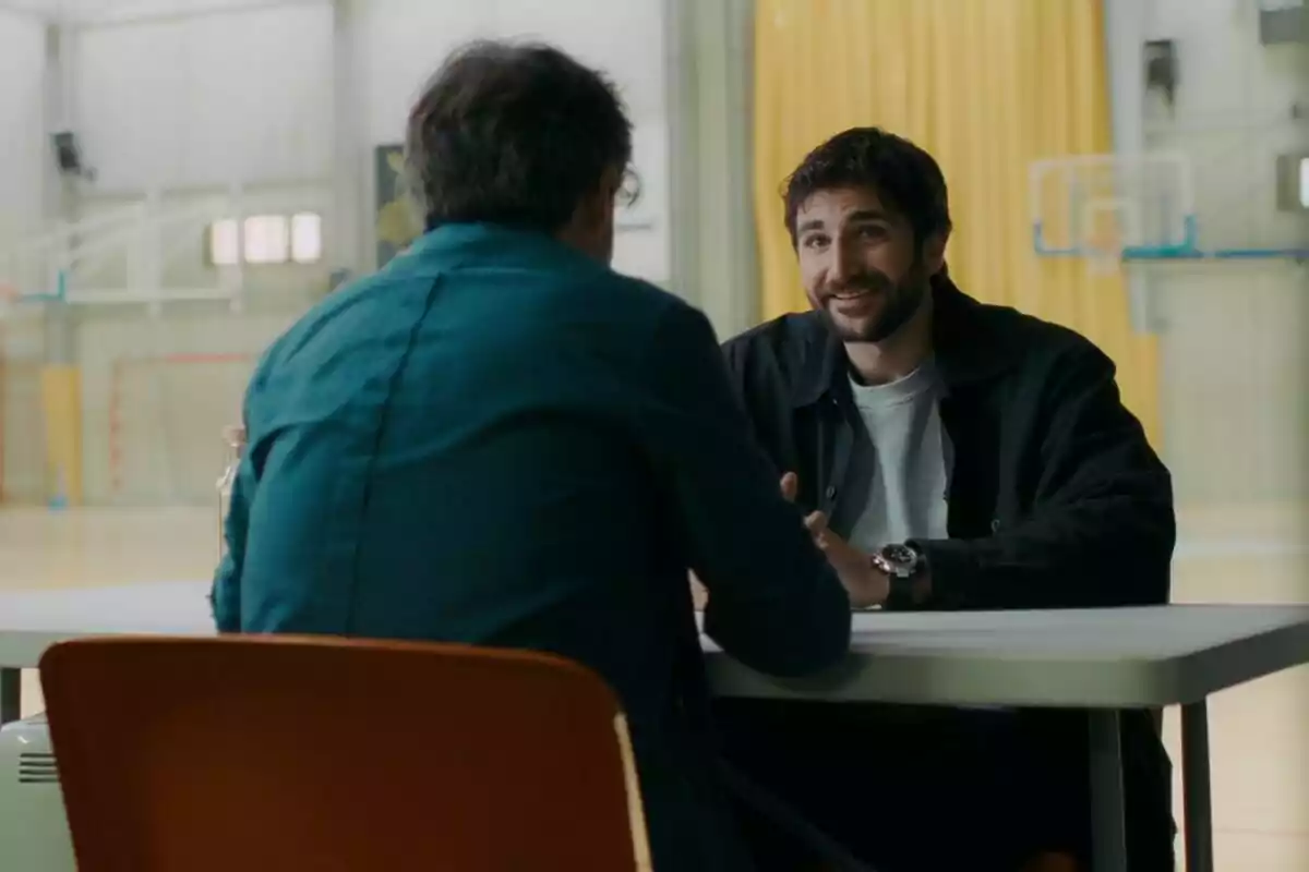 Ricky Rubio y Jordi Évole conversan sentados frente a frente en una mesa dentro de un gimnasio iluminado en Lo de Évole.