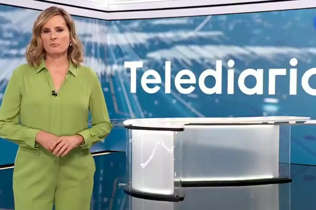 Ana Roldán vestida de verde en un estudio de televisión con la palabra Telediario en el fondo