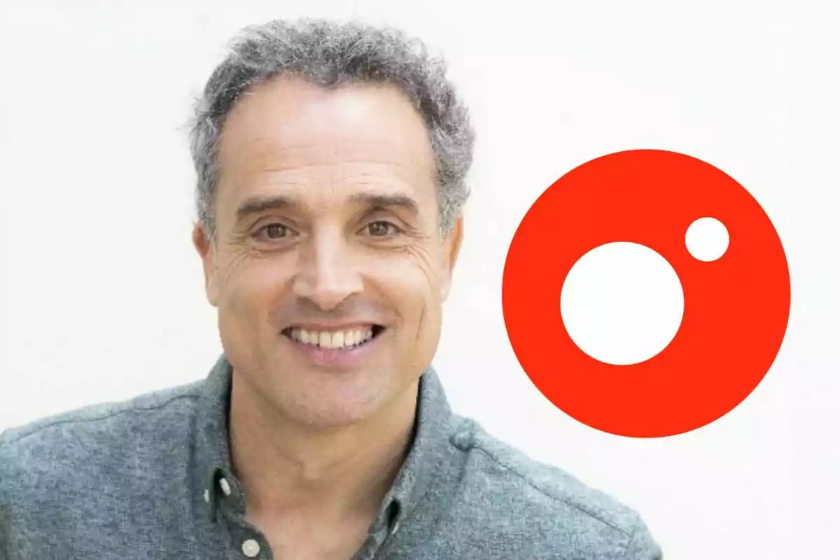 Daniel Guzmán de cabello canoso y camisa gris sonríe frente a un fondo claro con un logotipo rojo circular de Cuatro a su lado