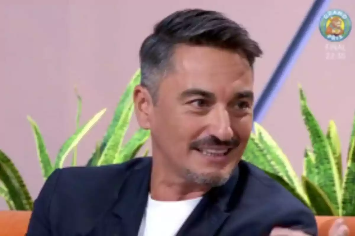 Diego Reinares de cabell curt i barba retallada somrient mentre està assegut en un plató de Mañaneros amb plantes al fons Diego Reinares de cabell curt i barba retallada somrient mentre està assegut en un plató de Mañaneros amb plantes al fons