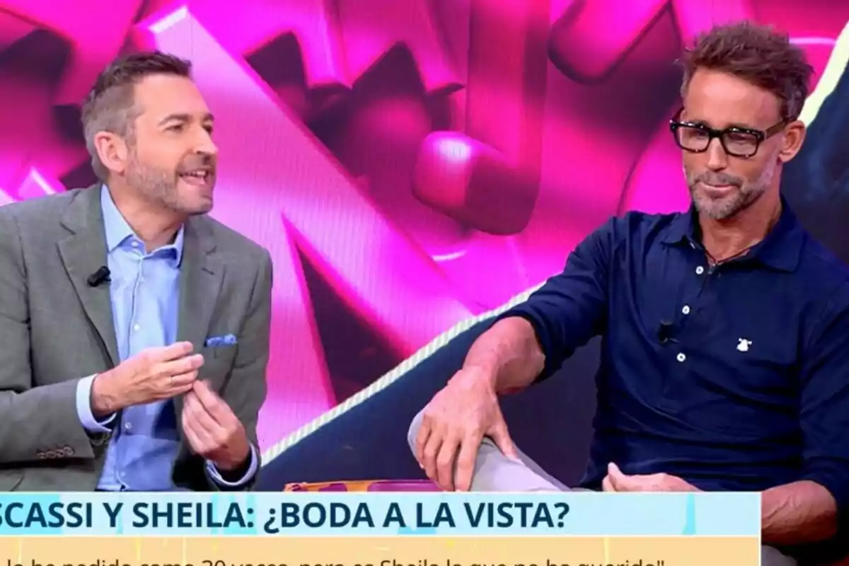 Frank Blanco y Álvaro Muñoz Escassi conversan en Tardear con fondo rosa y un rótulo en la parte inferior que menciona una posible boda