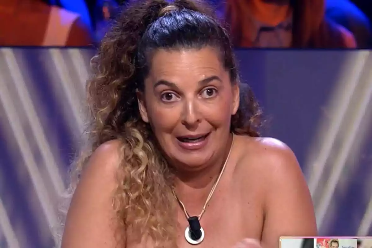 Tamara, hermana de Michu, de cabello rizado y recogido con una coleta alta, lleva un collar y está sentada en un plató de De Viernes con expresión facial de sorpresa o entusiasmo Tamara, hermana de Michu, de cabello rizado y recogido con una coleta alta, lleva un collar y está sentada en un plató de De Viernes con expresión facial de sorpresa o entusiasmo