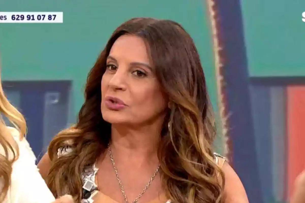 Dona de cabell llarg i ondulat castany parlant en un programa de televisió amb un fons acolorit Dona de cabell llarg i ondulat castany parlant en un programa de televisió amb un fons acolorit