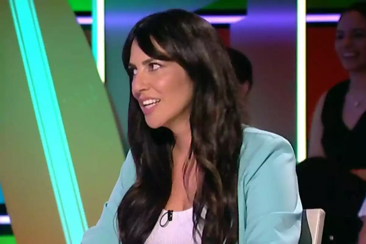 Irene Junquera de cabello largo y oscuro sentada en un set de Zapeando con luces de colores y personas al fondo Irene Junquera de cabello largo y oscuro sentada en un set de Zapeando con luces de colores y personas al fondo