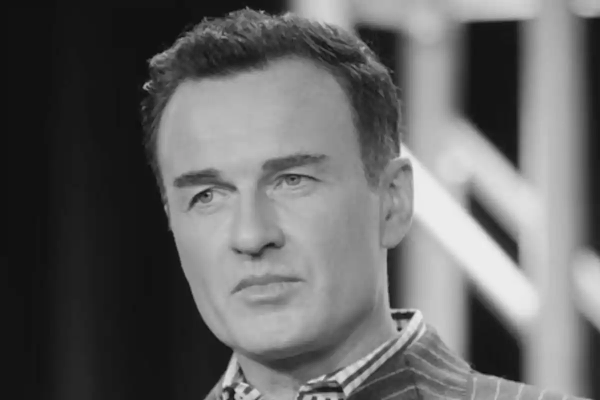Julian McMahon de cabello corto y expresión seria en una imagen en blanco y negro
