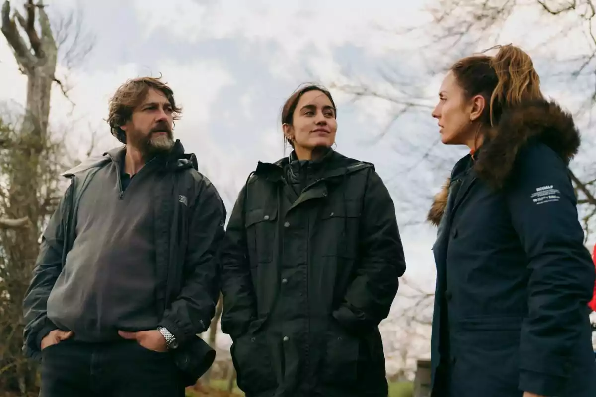 Megan Montaner, Félix Gómez y otra mujer con ropa de abrigo conversan al aire libre en un entorno natural con árboles y cielo nublado en La Caza: Irati. Megan Montaner, Félix Gómez y otra mujer con ropa de abrigo conversan al aire libre en un entorno natural con árboles y cielo nublado en La Caza: Irati.