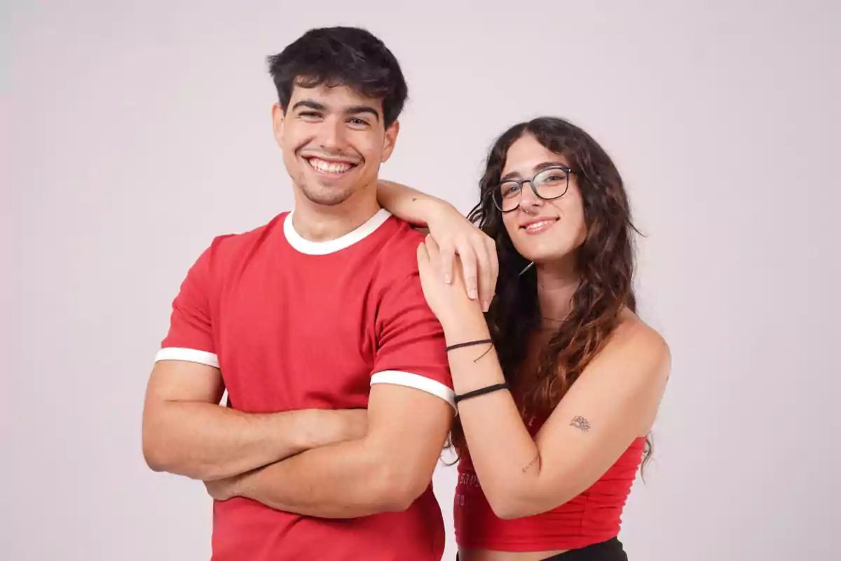 Jon García y Aida Fita sonríen y posan juntas, una de ellas lleva gafas y ambas visten ropa roja.