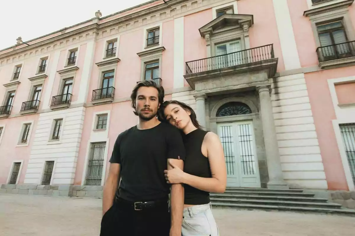 Carla Campra y Carlos Cuevas joven posa frente a un edificio antiguo de color rosa con grandes ventanas y puertas de hierro en Los secretos de la cortesana Carla Campra y Carlos Cuevas joven posa frente a un edificio antiguo de color rosa con grandes ventanas y puertas de hierro en Los secretos de la cortesana