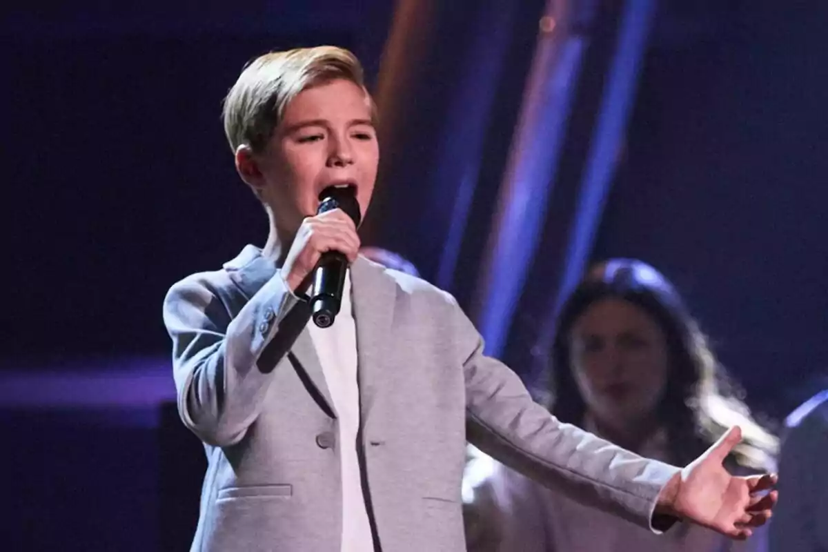 Lucas Paulano cantant en un escenari amb micròfon a la mà i fons fosc a La Voz Kids Lucas Paulano cantant en un escenari amb micròfon a la mà i fons fosc a La Voz Kids