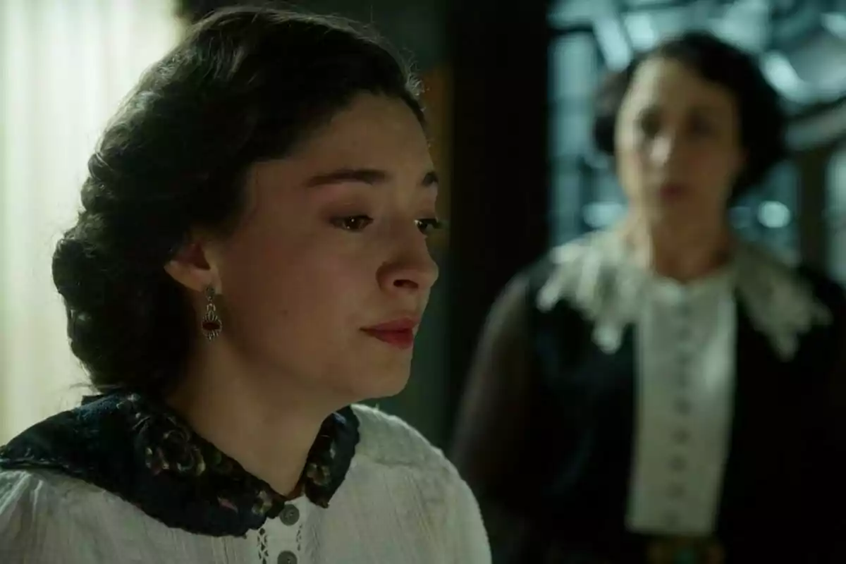 Marta Costa amb expressió trista i llàgrimes als ulls mentre una altra dona desenfocada apareix al fons a La Promesa Marta Costa amb expressió trista i llàgrimes als ulls mentre una altra dona desenfocada apareix al fons a La Promesa