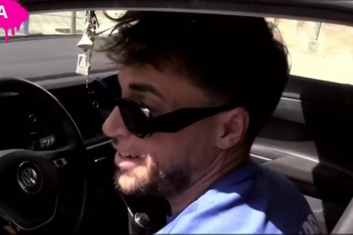 Montoya con barba y gafas de sol sentado en el asiento del conductor de un coche Volkswagen en Tardear