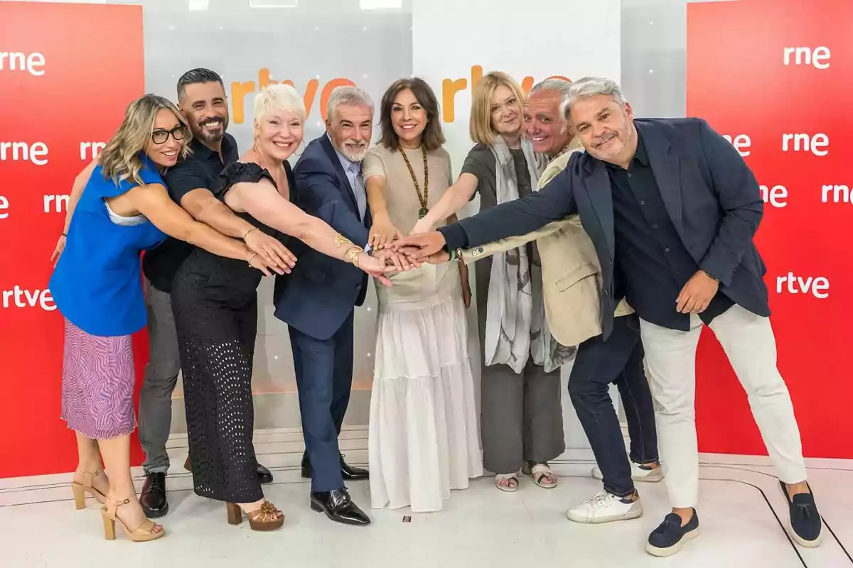 Un grupo de personas sonrientes formado por Juan Ramón Lucas, David Cantero, Isabel Gemio, Gorka Rodríguez, Rosa Molló, Ángeles Caso y Pepa Fernández posa unidas con las manos juntas al centro frente a un fondo con logotipos de RTVE y RNE Un grupo de personas sonrientes formado por Juan Ramón Lucas, David Cantero, Isabel Gemio, Gorka Rodríguez, Rosa Molló, Ángeles Caso y Pepa Fernández posa unidas con las manos juntas al centro frente a un fondo con logotipos de RTVE y RNE