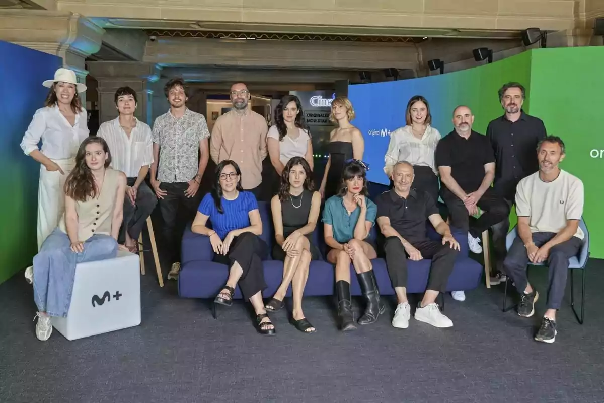 Grupo de personas posando juntas en un evento frente a un fondo de colores verde y azul con el logo de Movistar Plus