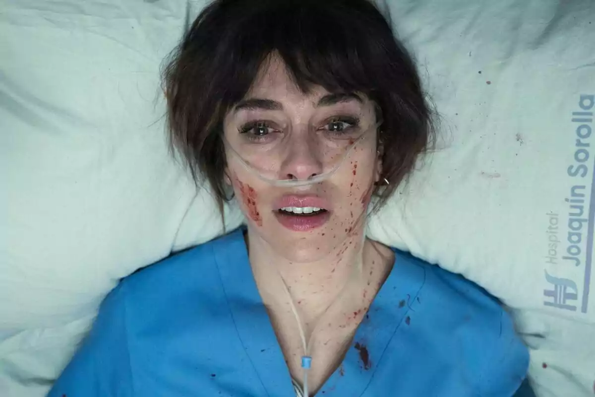 Blanca Suárez amb bata blava d’hospital estirada en un llit amb taques de sang a la cara i a l’uniforme, amb una cànula nasal d’oxigen i expressió d’angoixa a Respira