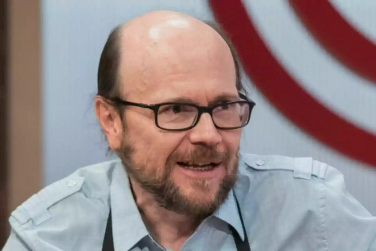 Santiago Segura calvo con barba y gafas hablando y vistiendo una camisa azul claro en MasterChef