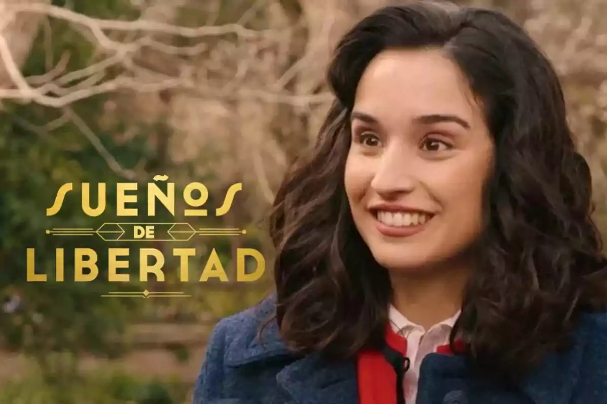 Sara Sanz de cabello oscuro sonriente con un abrigo azul y fondo de árboles, junto al texto Sueños de Libertad en letras doradas