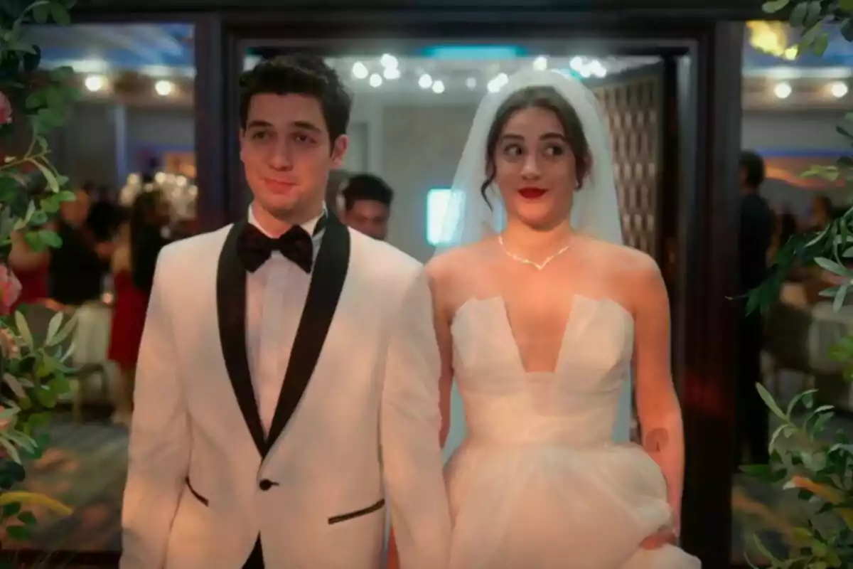 Seren y Uras como novios entrando a una boda, el hombre lleva esmoquin blanco y la mujer un vestido de novia con velo, ambos con expresiones divertidas en Renacer Seren y Uras como novios entrando a una boda, el hombre lleva esmoquin blanco y la mujer un vestido de novia con velo, ambos con expresiones divertidas en Renacer