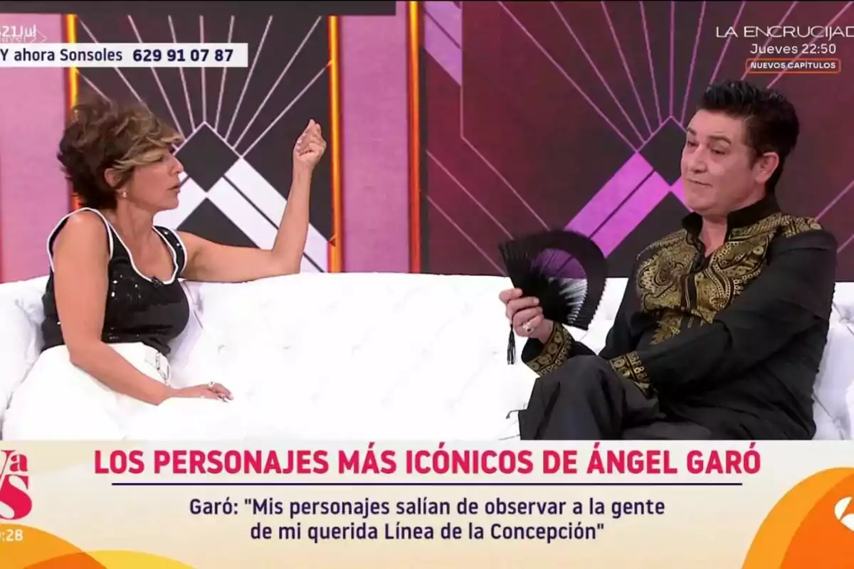 Sonsoles Ónega y Ángel Garó conversan en un set de Y ahora Sonsoles, una de ellas sostiene un abanico negro y viste una camisa con detalles dorados, mientras la otra lleva un conjunto blanco y negro y gesticula con la mano, el fondo es geométrico y en la parte inferior aparece un texto sobre los personajes icónicos de Ángel Garó. Sonsoles Ónega y Ángel Garó conversan en un set de Y ahora Sonsoles, una de ellas sostiene un abanico negro y viste una camisa con detalles dorados, mientras la otra lleva un conjunto blanco y negro y gesticula con la mano, el fondo es geométrico y en la parte inferior aparece un texto sobre los personajes icónicos de Ángel Garó.