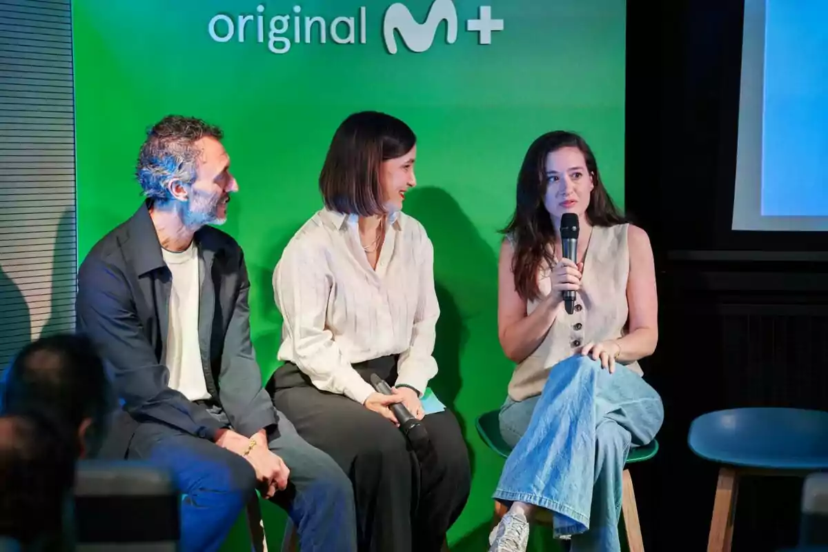 Jorge Pezzi, una mujer y Victoria Martín conversan en un panel frente a un fondo verde con el logo de Movistar Plus, una de ellas sostiene un micrófono mientras habla. Jorge Pezzi, una mujer y Victoria Martín conversan en un panel frente a un fondo verde con el logo de Movistar Plus, una de ellas sostiene un micrófono mientras habla.