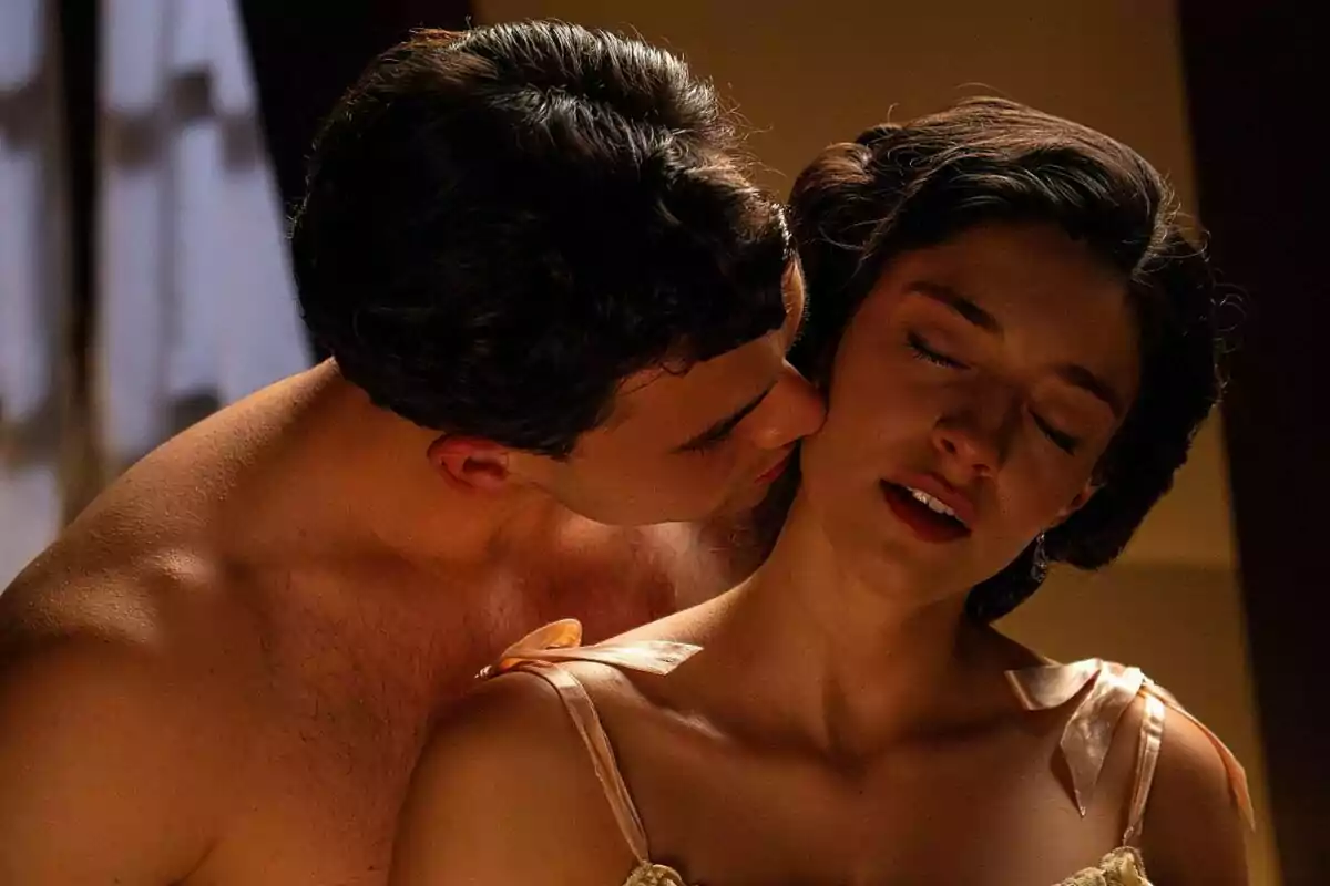 Xavi Lock y Marta Costa en una escena íntima donde un hombre besa el cuello de una mujer que tiene los ojos cerrados y parece disfrutar el momento en La Promesa. Xavi Lock y Marta Costa en una escena íntima donde un hombre besa el cuello de una mujer que tiene los ojos cerrados y parece disfrutar el momento en La Promesa.