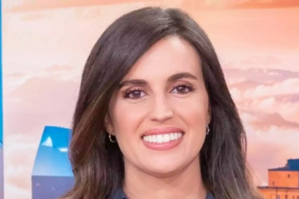 Aida Bao de cabello castaño oscuro y liso sonriendo frente a un fondo con colores cálidos y edificios desenfocados en Malas Lenguas