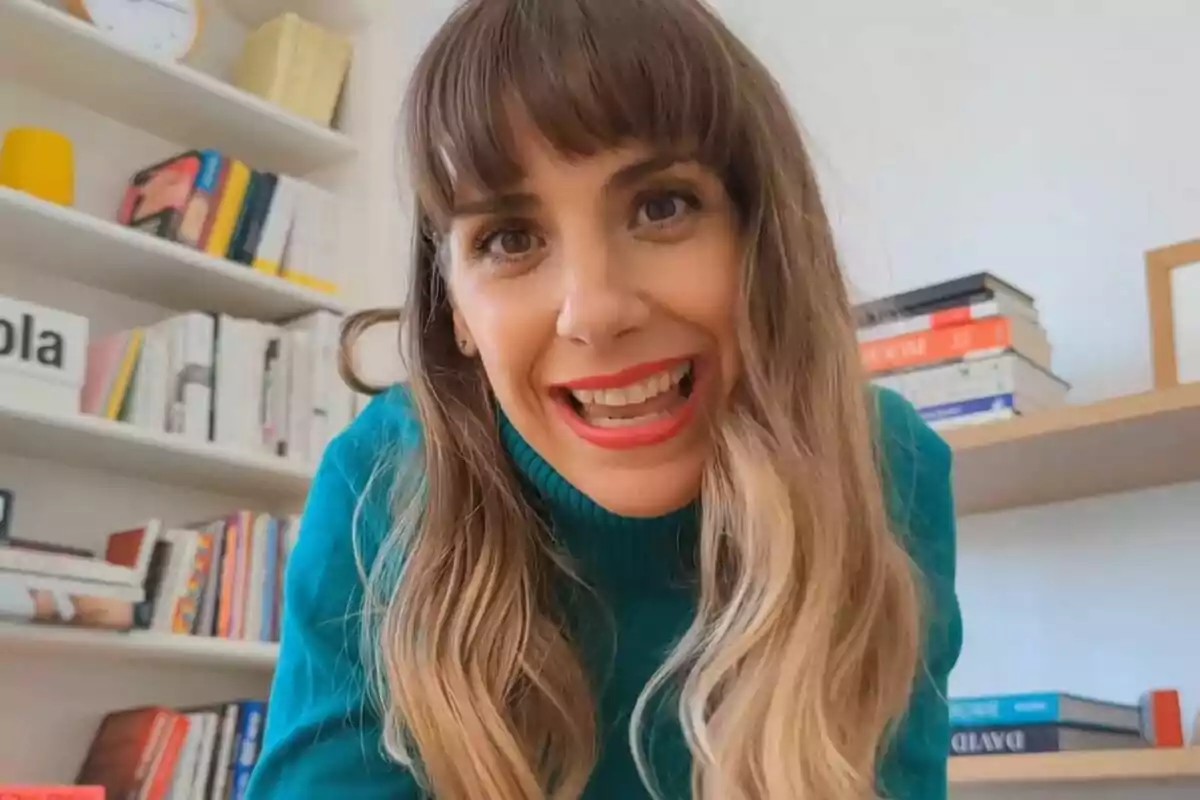 Bibiana Ballbè con cabello largo y ondulado sonríe frente a la cámara en una habitación con estanterías llenas de libros. Bibiana Ballbè con cabello largo y ondulado sonríe frente a la cámara en una habitación con estanterías llenas de libros.