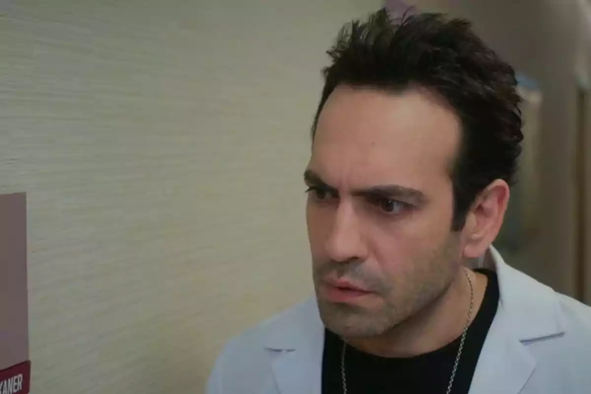 Evren amb bata blanca i expressió seriosa mirant cap a un costat en un passadís interior a Renéixer Evren amb bata blanca i expressió seriosa mirant cap a un costat en un passadís interior a Renéixer