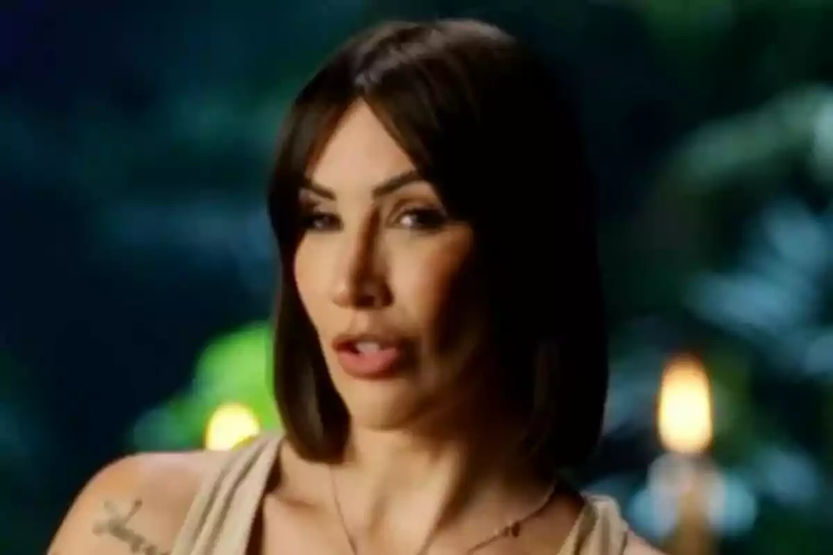 Fani Carbajo de cabello oscuro y liso con expresión seria, fondo desenfocado con luces cálidas en Supervivientes All Stars.