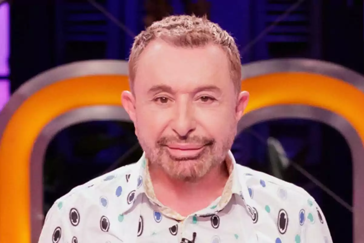 José Manuel Parada de cabello corto y barba recortada con camisa estampada de círculos en un set de MasterChef Celebrity iluminado con luces naranjas y fondo oscuro