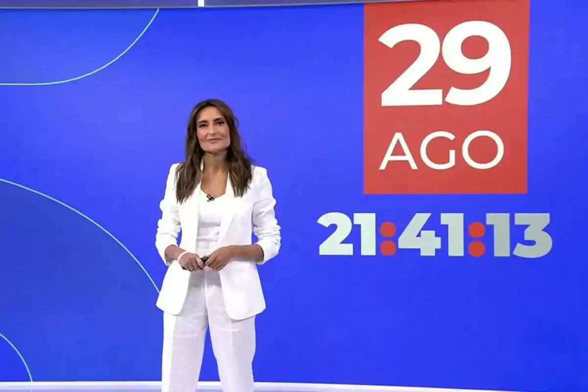 Leticia Iglesias vestida de blanco frente a una pantalla azul que muestra la fecha 29 de agosto y la hora 21 41 13 en informativos Telecinco Leticia Iglesias vestida de blanco frente a una pantalla azul que muestra la fecha 29 de agosto y la hora 21 41 13 en informativos Telecinco