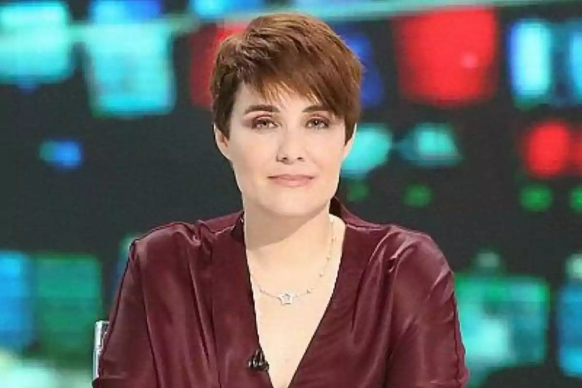 Marta Solano de cabell curt castany amb una brusa burdeus asseguda davant d’un fons desenfocat de colors brillants
