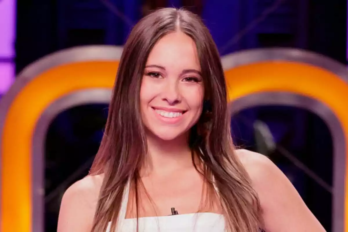 Masi de cabell llarg i llis somriu davant d’un fons acolorit en un estudi de MasterChef Celebrity.
