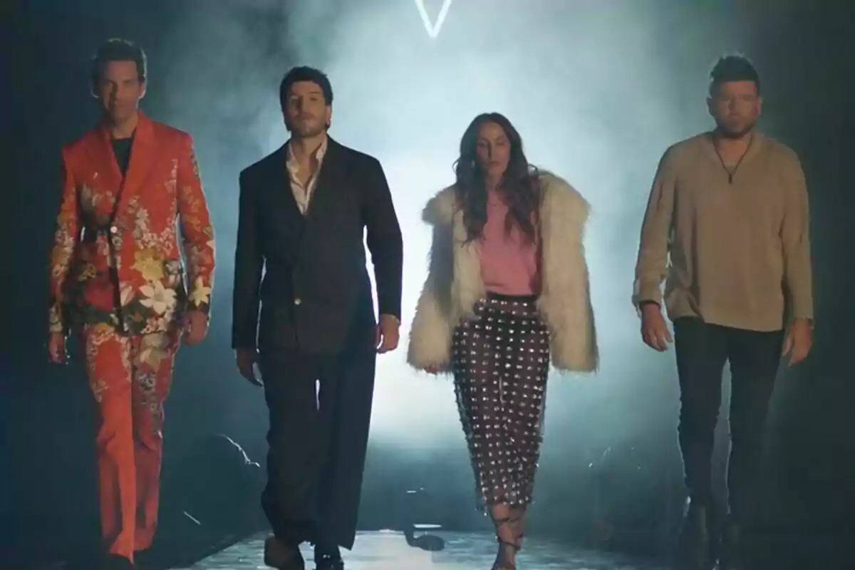 Mika, Sebastian Yatra, Malú y Pablo López caminan hacia el frente en un escenario con humo y luz de fondo, cada una con un estilo de ropa llamativo y diferente en el tráiler de La Voz.