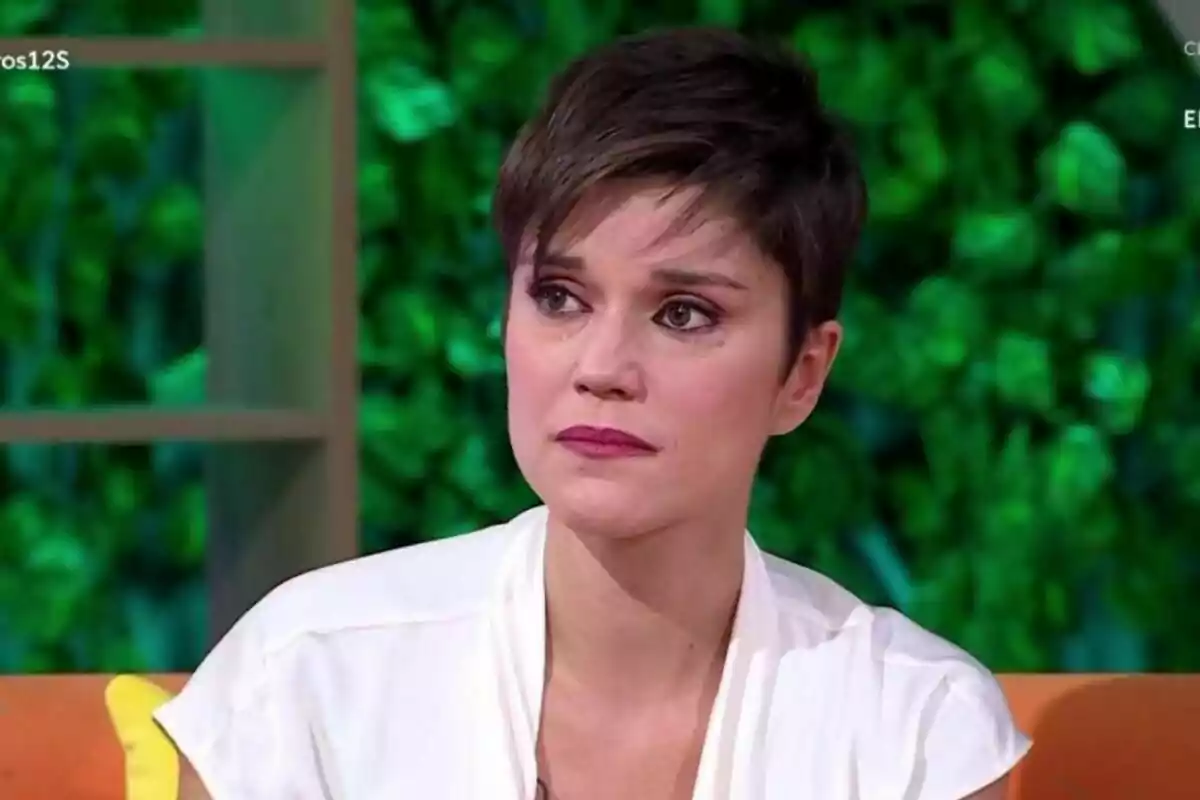 Miriam Moreno de cabello corto y oscuro con expresión seria y lágrimas en los ojos, sentada en un sofá con fondo de plantas verdes en Mañaneros. Miriam Moreno de cabello corto y oscuro con expresión seria y lágrimas en los ojos, sentada en un sofá con fondo de plantas verdes en Mañaneros.