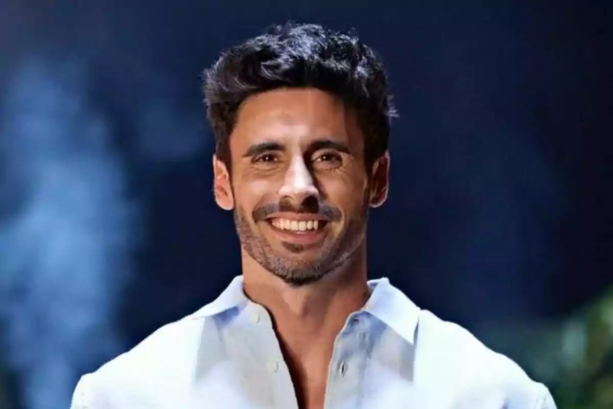 Noel Bayarri, jove de cabell fosc i barba curta, somrient i vestint una camisa clara amb un fons fosc desenfocat a Supervivientes All Stars.