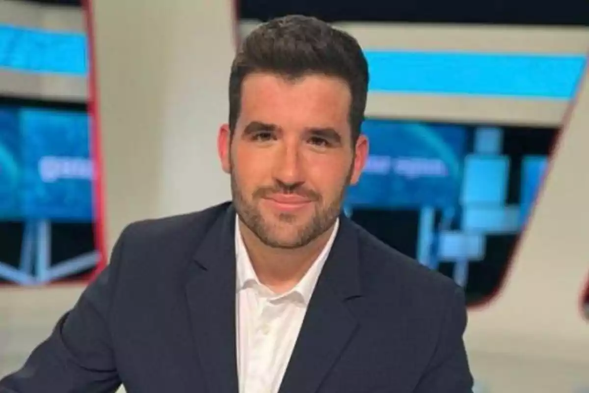 Odei Esnaola joven con barba y cabello corto vestido con saco oscuro y camisa blanca en un estudio de televisión Odei Esnaola joven con barba y cabello corto vestido con saco oscuro y camisa blanca en un estudio de televisión