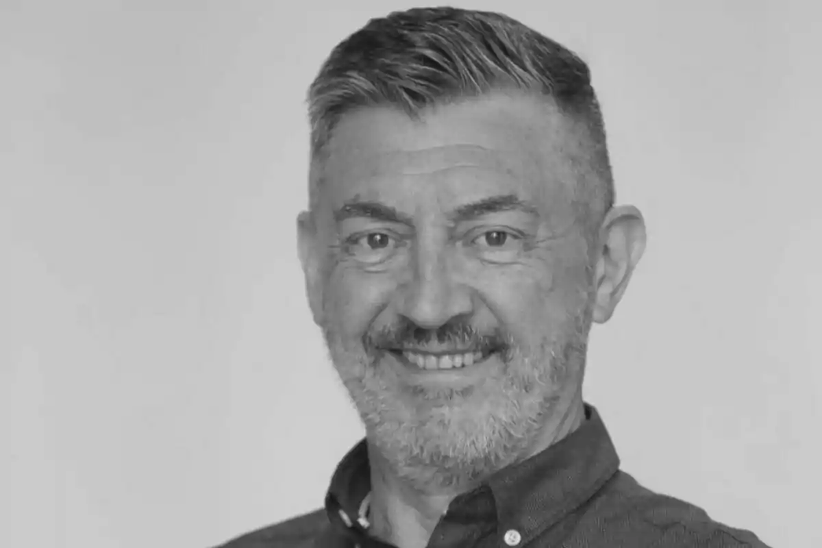 Ricardo Medina de mitjana edat amb barba i cabell curt pentinat cap a un costat somrient i vestint una camisa fosca en una foto en blanc i negre
