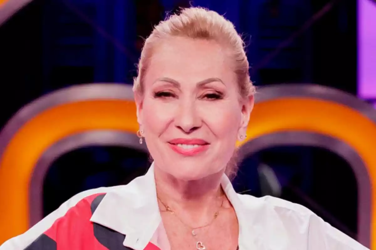 Rosa Benito, rossa de mitjana edat somrient amb els cabells recollits i un fons colorit desenfocat a MasterChef Celebrity
