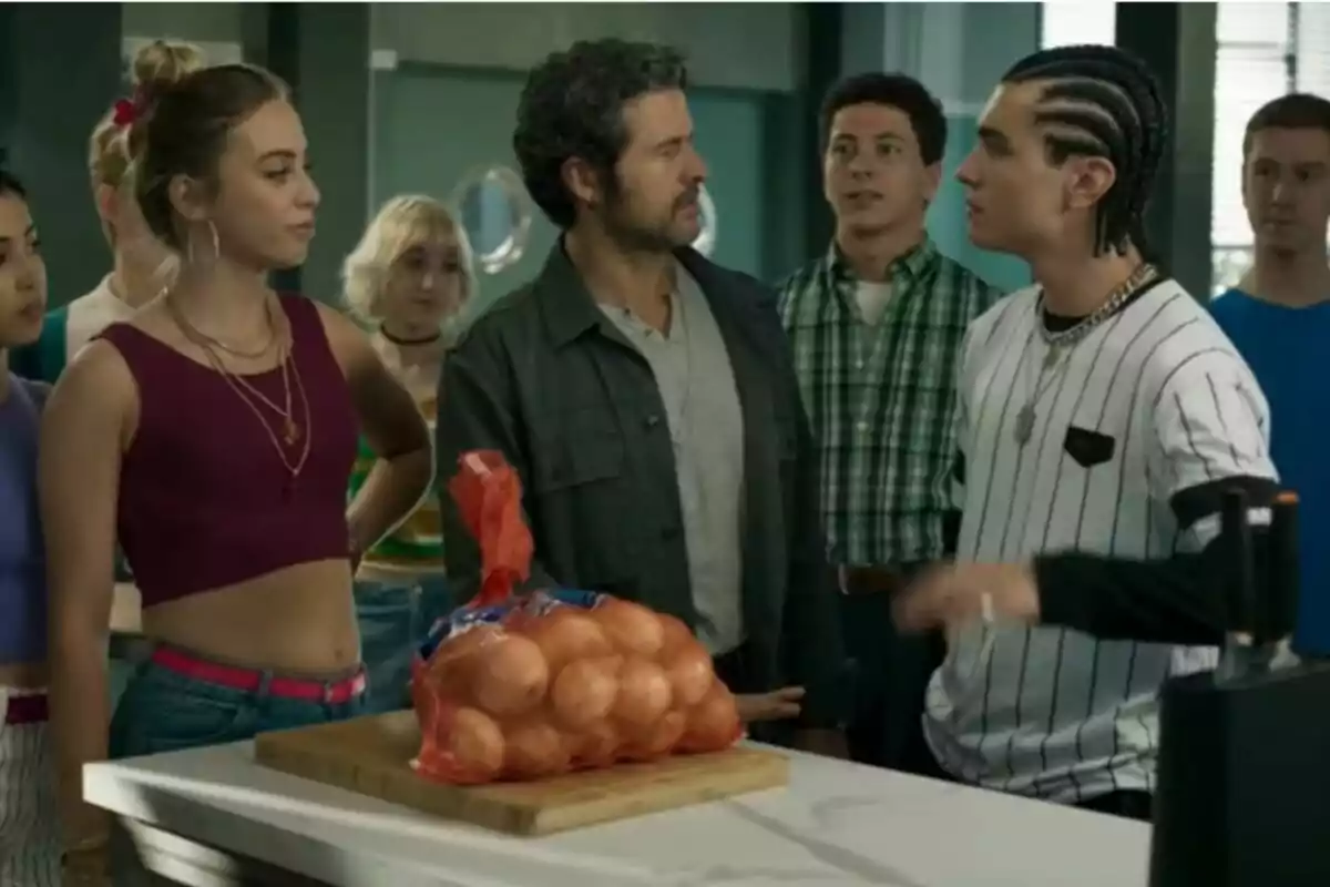 Un grup de persones encapçalat per Diego Martín està reunit en una cuina al voltant d’una taula on hi ha una bossa de cebes a la sèrie Sense Gluten. Un grup de persones encapçalat per Diego Martín està reunit en una cuina al voltant d’una taula on hi ha una bossa de cebes a la sèrie Sense Gluten.
