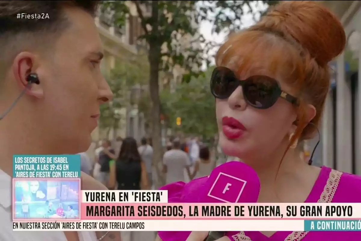 Yurena amb ulleres de sol i llavis vermells sosté un micròfon rosa de Festa mentre és entrevistada per Omar Suárez amb auriculars en un carrer concorregut Yurena amb ulleres de sol i llavis vermells sosté un micròfon rosa de Festa mentre és entrevistada per Omar Suárez amb auriculars en un carrer concorregut
