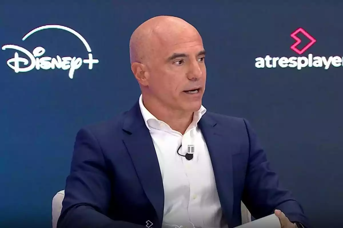 José Antonio Antón calvo con traje azul y camisa blanca hablando en un panel con los logotipos de Disney Plus y Atresplayer en el fondo José Antonio Antón calvo con traje azul y camisa blanca hablando en un panel con los logotipos de Disney Plus y Atresplayer en el fondo