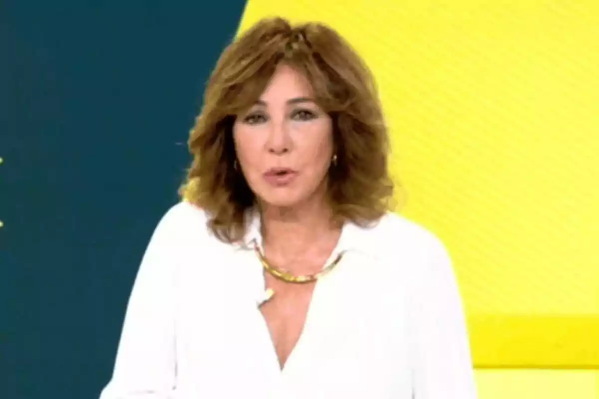 Ana Rosa Quintana de cabell castany i ondulat amb camisa blanca i collaret daurat davant d’un fons groc i verd fosc a El Programa de Ana Rosa Ana Rosa Quintana de cabell castany i ondulat amb camisa blanca i collaret daurat davant d’un fons groc i verd fosc a El Programa de Ana Rosa